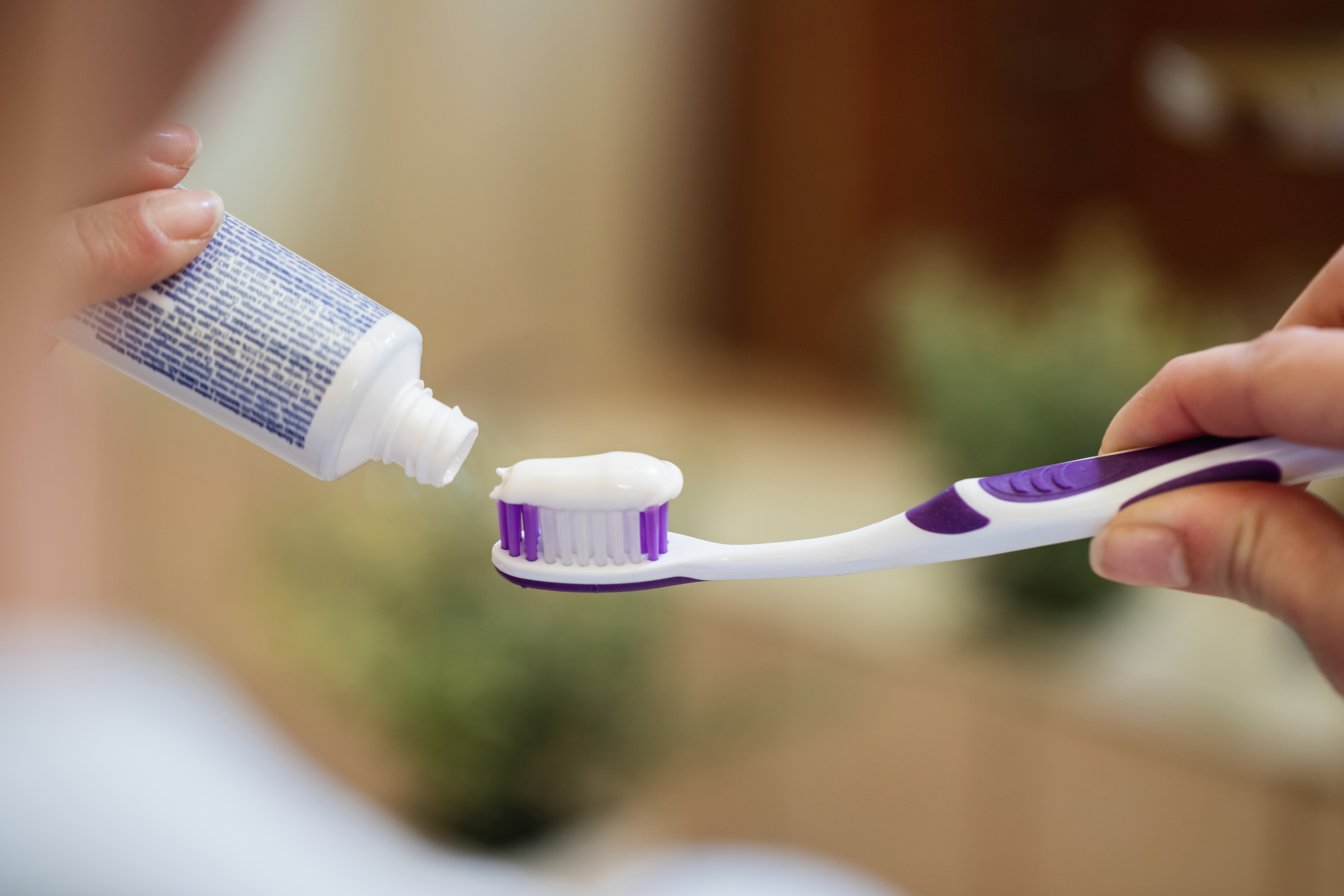 Close-up of woman applying toothpaste on a toothbrush.